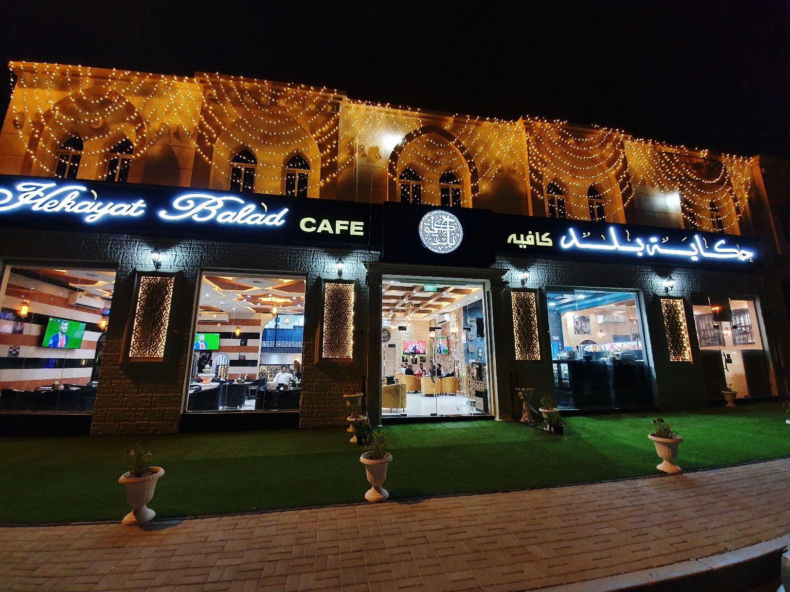 واجهة مطعم وكافيه حكاية بلد مضاءة ليلاً